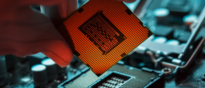 A close-up of an advanced semiconductor chip held above a motherboard, symbolising AI computing and next-generation technology.